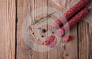 Raw smoked sausage lies on an old wooden table with spices, herbs and spices