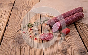 Raw smoked sausage lies on an old wooden table with spices, herbs and spices. Background for design