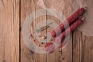 Raw smoked sausage lies on an old wooden table with spices, herbs and spices. Background for design