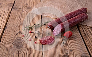 Raw smoked sausage lies on an old wooden table with spices, herbs and spices. Background for design. low key