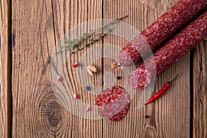 Raw smoked sausage lies on an old wooden table with spices, herbs and spices. View from above. Background for design