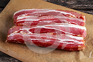 Raw smoked streaky sliced bacon on crumpled paper