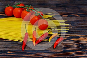 raw spaghetti bavette with tomatoes, pepper ingredients for cooking Italian pasta. Fresh vegetables and uncooked italian pasta on