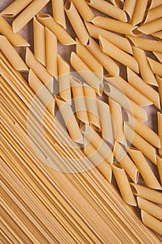 Raw spaghetti on brown parchment, paper background. Close-up pasta, top view. Texture of yellow macaroni. Pattern of italian pasta