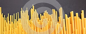 Raw spaghetti and macaroni pasta on black background, banner