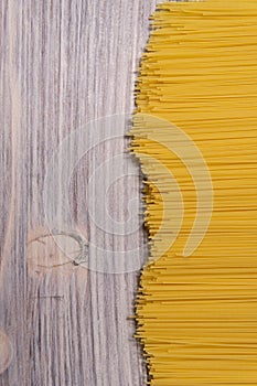 raw spaghetti pasta scattered on wooden table, close-up view from above