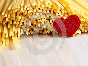 Raw spaghetti with red heart on a wooden bakground