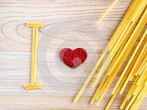 Raw spaghetti with red heart on a wooden bakground