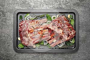 Raw spare ribs with herbs and seasonings on grey table, top view