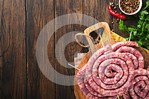 Raw spiral pork sausages. Fresh pork sausages tasty twisted spiral for bbq on white stand with spices and herbs for Octoberfest pa