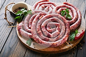 Raw spiral pork sausages. Fresh pork sausages tasty twisted spiral for bbq on white stand with spices and herbs for Octoberfest pa