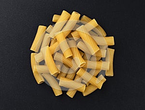 Raw spiral tortiglioni pasta isolated on black background, top view