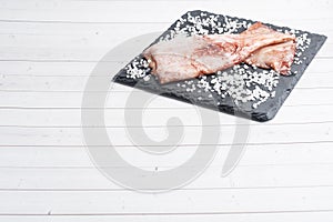 Raw squid carcass with spices and coarse salt on a black slate board. copy space Top view