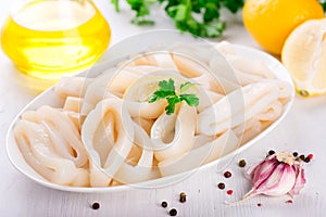 Raw squid rings on white plate, ready to cook