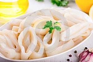 Raw squid rings on white plate, ready to cook