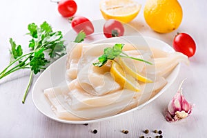 Raw squids and ingredients on the white plate