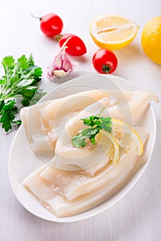 Raw squids and ingredients on the white plate