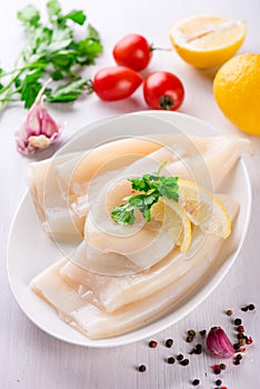 Raw squids and ingredients on the white plate