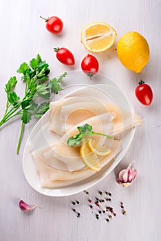 Raw squids and ingredients on the white plate