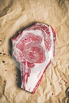 Raw steak rib-eye with seasoning on craft paper, copy space
