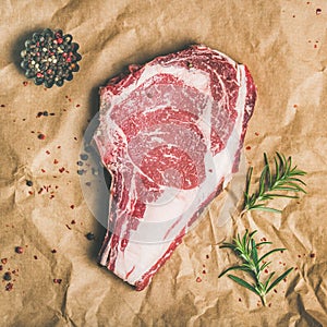 Raw steak rib-eye with seasoning on craft paper, square crop