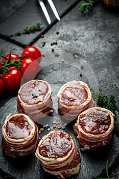 Raw steak Tenderloin fillet wrapped in bacon on a dark background, filet Mignon. top view vertical image, place for text