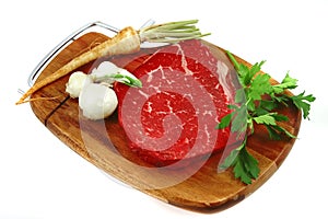 Raw steak on wooden board and vegetables