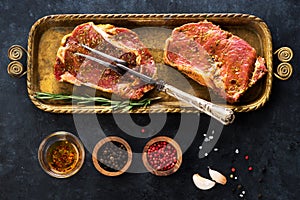 Raw steaks ribeye, fork for meat, spices and herbs