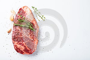 Raw striploin beef steak with rosemary, thyme, salt and pepper. isolated against white. top view with copy space