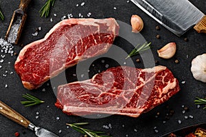 Raw striploin and bone-steak with knife and spices