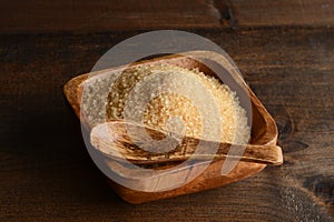 Raw sugar in bowl with wooden spoon