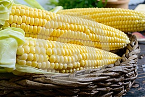 Raw sugar corn, sea salt, spices, herbs, butter on a dark wooden table.