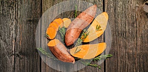 Raw sweet potato on wooden background. Long banner format. top view