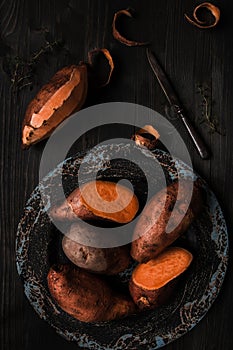 Raw sweet potato on the wooden black table top view