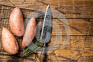 Raw sweet potatoes on kitchen table, fresh batata. Wooden background. Top view. Copy space