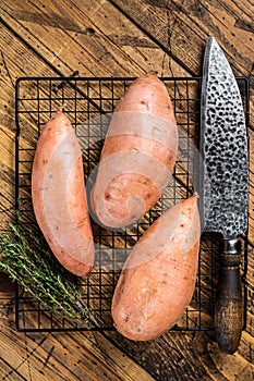 Raw sweet potatoes on kitchen table, fresh batata. Wooden background. Top view