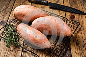 Raw sweet potatoes on kitchen table, fresh batata. Wooden background. Top view