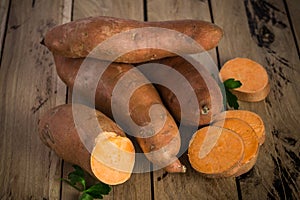 Raw sweet potatoes on rustic wooden background.