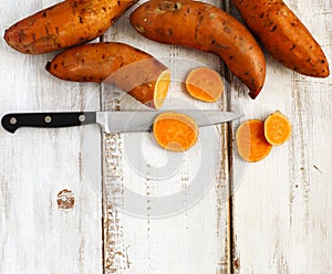 Raw sweet potatoes on wooden background