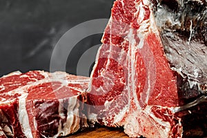 Raw T-bone steak cooking on stone dark table.
