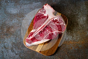 Raw T-bone steak cooking on stone table. Top view with copy space