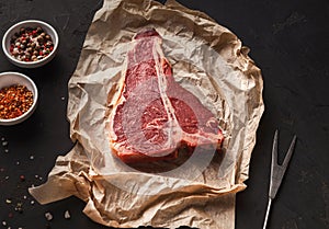 Raw t-bone steak on craft papper on dark background