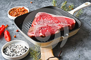 Raw T-Bone Steak in a grill pan with seasoning and Carolina reaper pepper