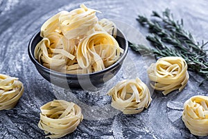 Raw tagliatelle nido on the flour-dusted black wooden background