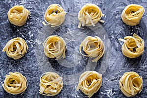 Raw tagliatelle nido on the flour-dusted black wooden background