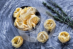 Raw tagliatelle nido on the flour-dusted black wooden background