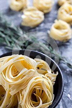 Raw tagliatelle nido on the flour-dusted black wooden background