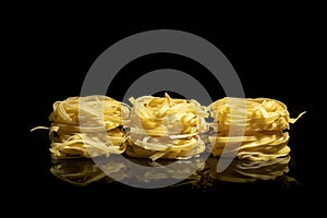 Raw tagliatelle pasta on black background