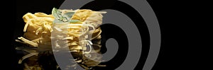 Raw tagliatelle pasta on black background