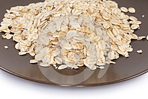 Raw thick-rolled oats on brown dish close-up